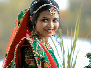 A smiling woman representing regional influencers in india similing and wearing brightly colored traditional clothes