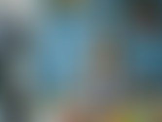 Smiling woman in plaid holds a mug in a kitchen. Camera on tripod, blue wall, veggies on counter. Cozy and casual vibe.