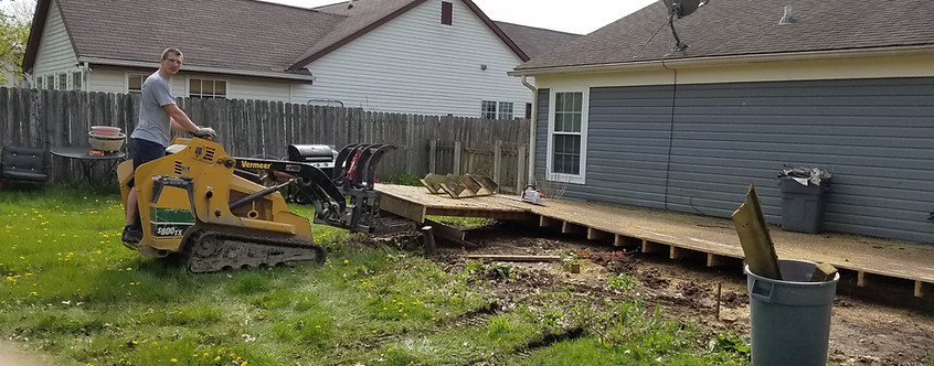 John Schott using a mini skid steer to professionally dismantle and remove a wooden deck from the back of an Indianapolis home.
