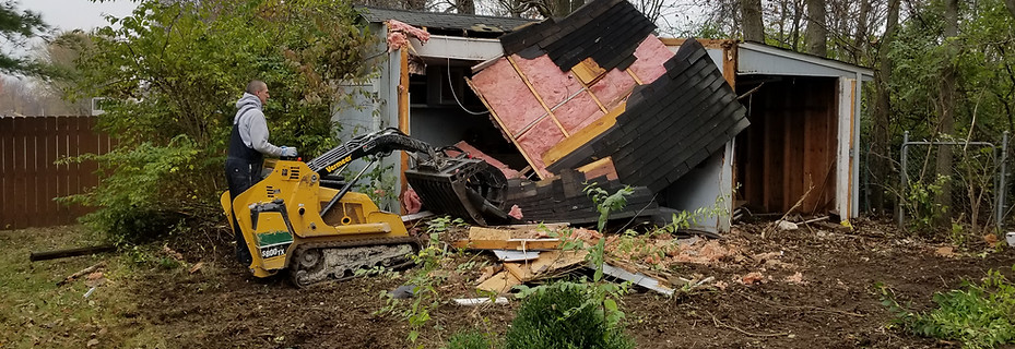 ohn Schott operating a mini skid steer to dismantle a small wooden garage in an Indianapolis backyard.