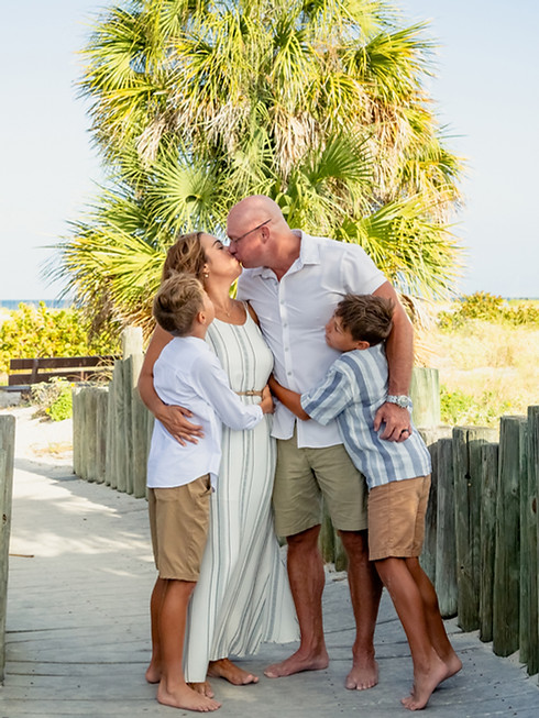 Family on a beach boardwalk with palm tree, horizontal image