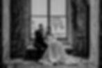bride and groom sharing a playful moment by a large window in a black-and-white wedding portrait