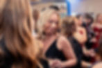 Woman in black dress smiling at a crowded event