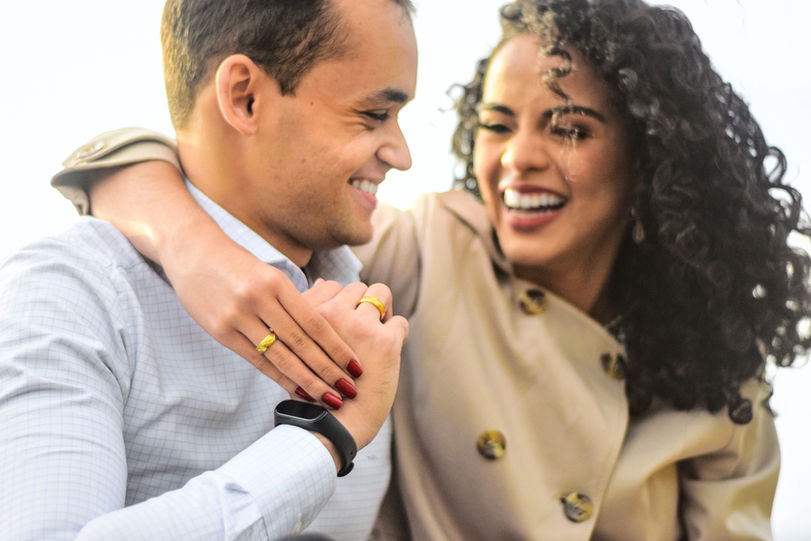 Um jovem casal feliz, usando alianças de noivado.