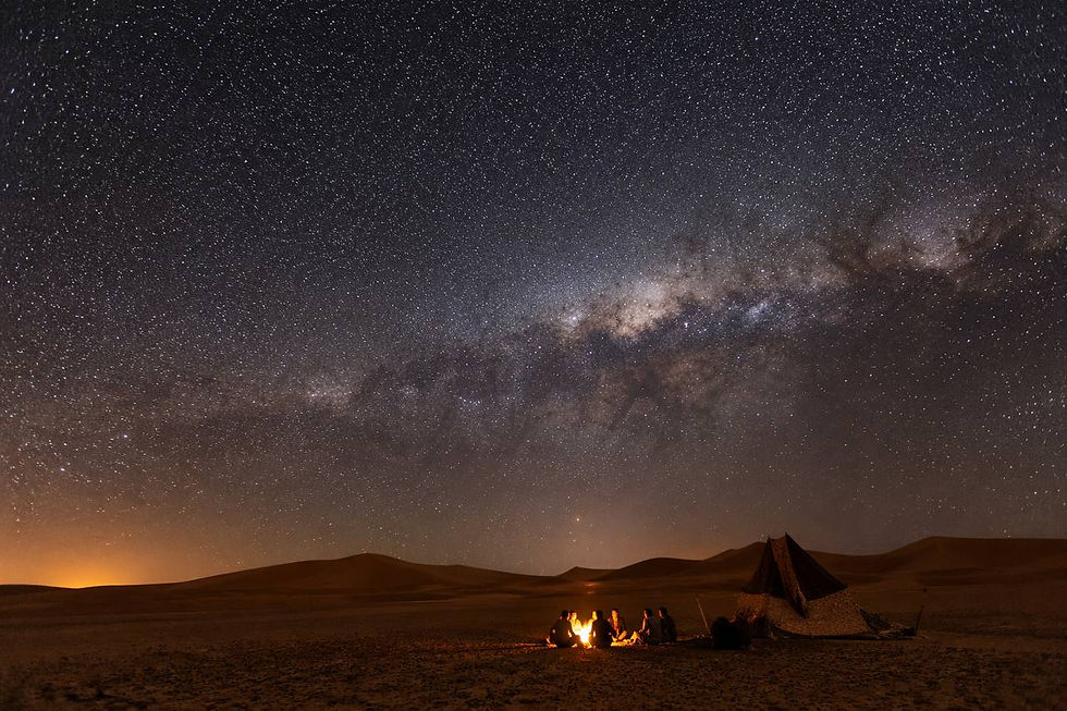 Un cielo notturno pieno di stelle sopra le dune del deserto del Sahara a Merzouga, con la Via Lattea visibile e la sabbia illuminata dalla luce naturale delle stelle.
