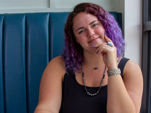 Kailee Nauman of Eclectic Designs .CO is looking at the camera smiling with purple hair
