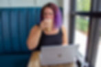 Kailee Nauman of Eclectic Designs .CO sitting at a Denver, CO coffee shop in front of her laptop drinking coffee
