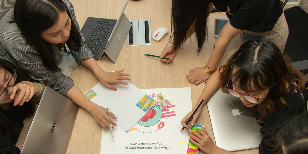 Five people collaborating around a table with laptops and colorful documents. They are focused and engaged in a discussion.