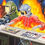 Thumbnail: painting of a robot wearing a red top, wearing an astronauts helmet. a fire raging behind him