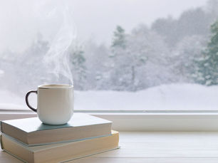 coffee mug on books in front of winter window view