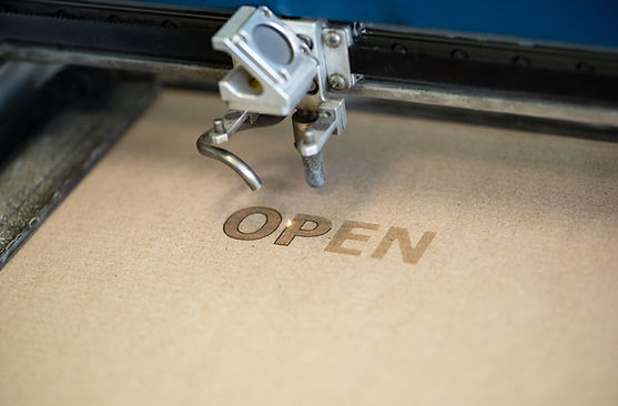 Industrial laser engraving word _open_ on a cardboard, close up view .jpg