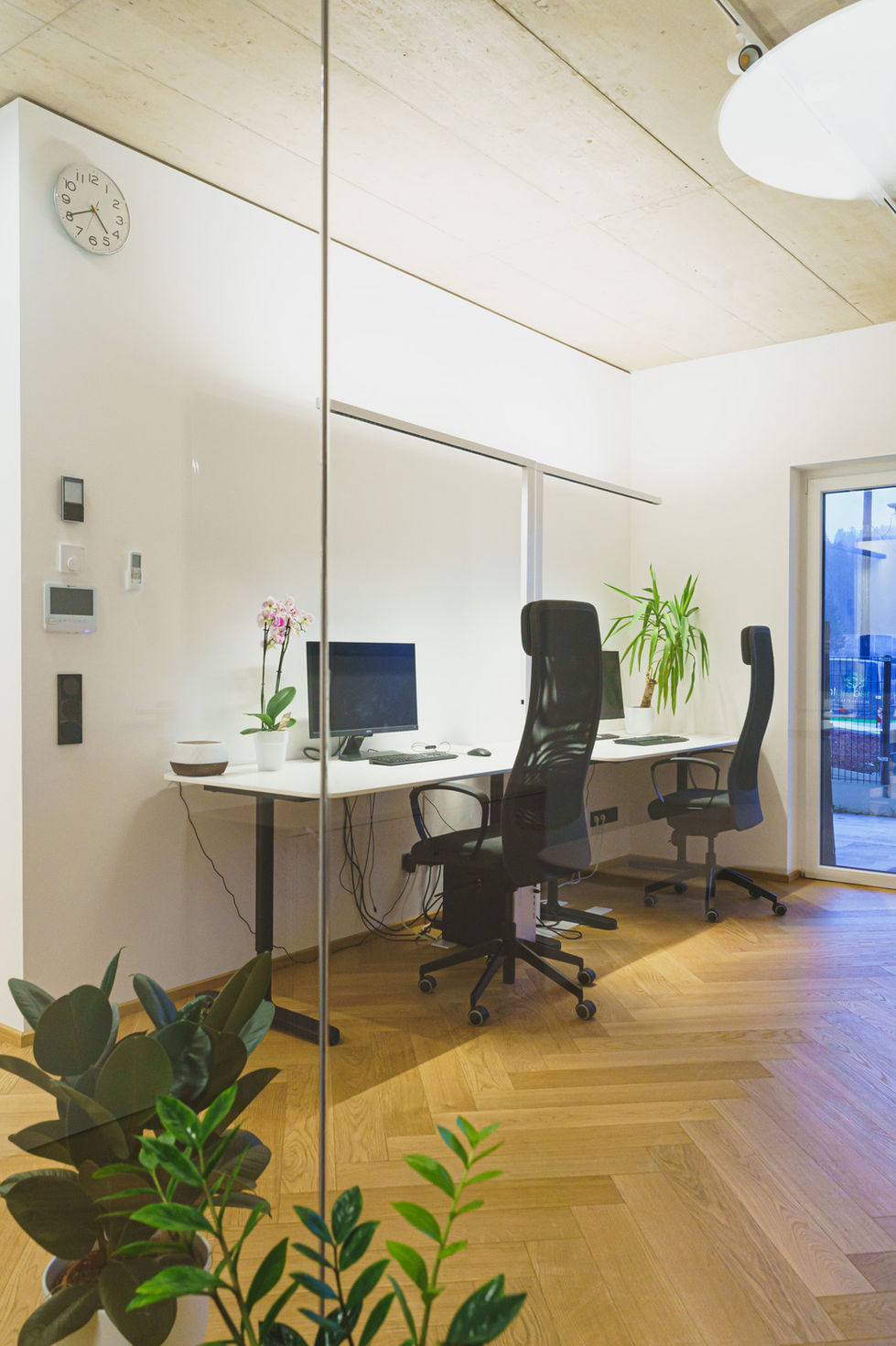 Zwei Tische in einem Büro mit zwei Bürosesseln und Bildschirmen auf den Tischen.