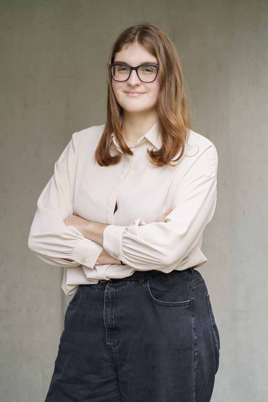 Eine Frau posiert für ein Businessportrait und verschränkt dabei ihre Arme.