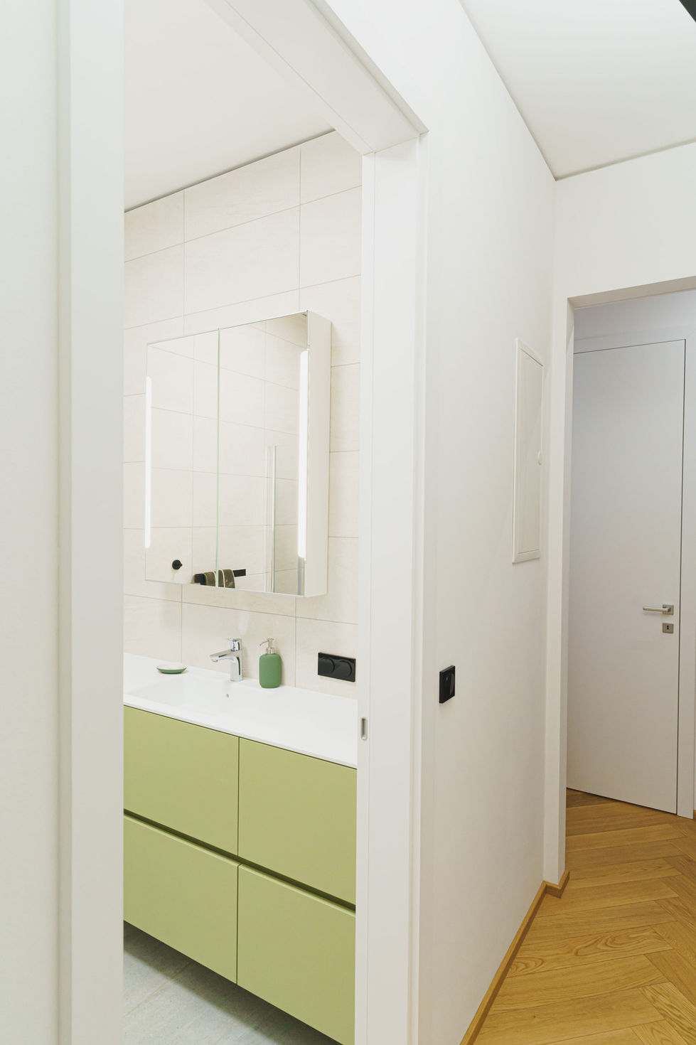Ein Gang eines Büro's, eine Tür ist offen und zeigt das grüne Waschbecken eines Badezimmers.