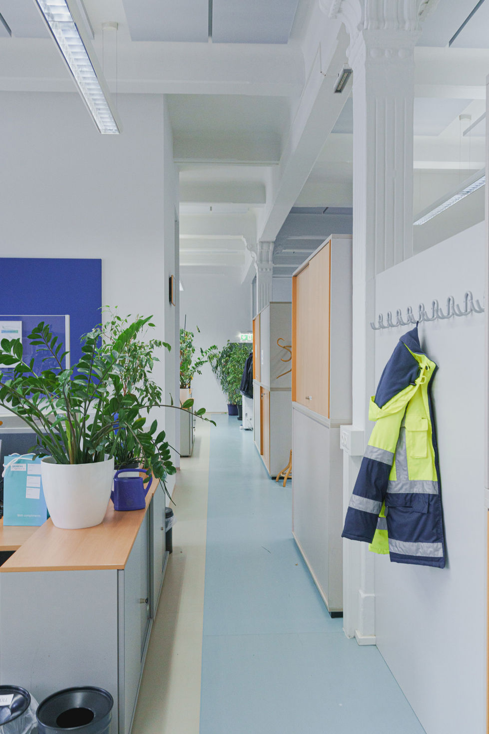 Gang eines leeren Büroräumen, eine Arbeitsjacke hängt an einem Hacken an der Wand.