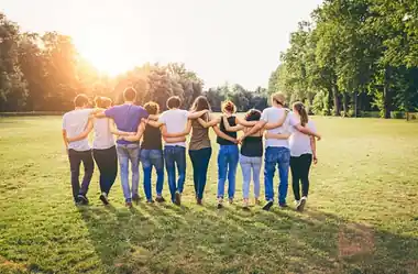 A group of friends standing arm in arm in a sunny park