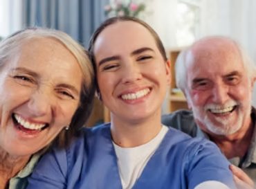 Smiling caregiver with an older couple at home