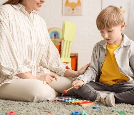 Caregiver and boy playing a xylophone together