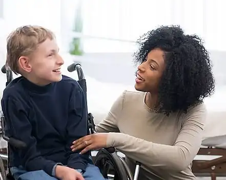 Caregiver talking with a young man in a wheelchair