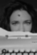 Creative portrait of a woman peeking over a vintage typewriter photographed by a Niagara portrait photographer.