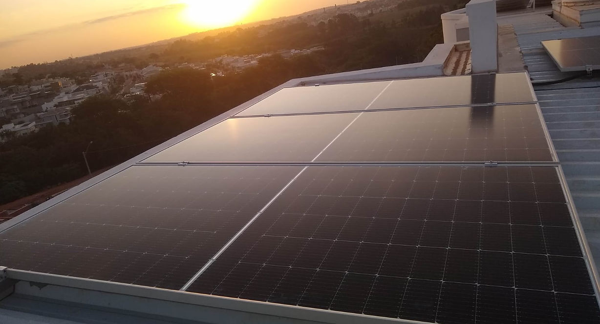 Painéis solares instalados em cobertura durante o pôr do sol, destacando a geração de energia limpa, economia e aproveitament