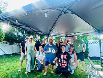 Birthday party guests posing with an Umami Hibachi chef under a backyard canopy