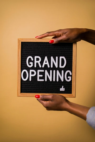 Hands holding a Grand Opening sign