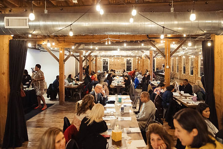 Large group of people seated at tables in a warmly lit venue with wooden beams during a BCTRHT community event.