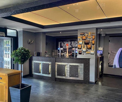 A full bar wrap featuring a sleek and modern design, covering the entire bar area with stylish graphics and branding elements. Adjacent to the bar, an opaque Perspex roof light installation provides natural light while maintaining privacy, contributing to the contemporary aesthetic of the space