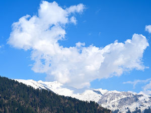 Massive clouds building over snowy Himalayan ridges near Dhungri in Manali.