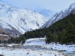 Snow-covered Himalayan landscape with the frozen Baspa River flowing out of Chitkul village, Kinnaur, India.