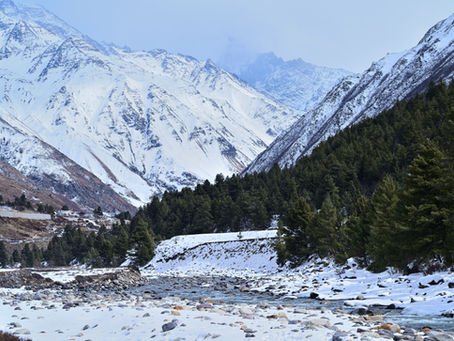 Snow-covered Himalayan landscape with the frozen Baspa River flowing out of Chitkul village, Kinnaur, India.