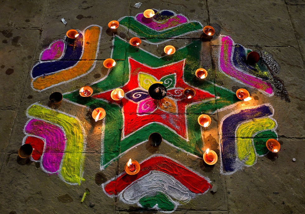 A colorful rangoli design crafted with vibrant powders on a stone ghat at night during Dev Diwali, illuminated by several small diyas. The intricate patterns glow softly, symbolizing the luminous and challenging journey of the festival.