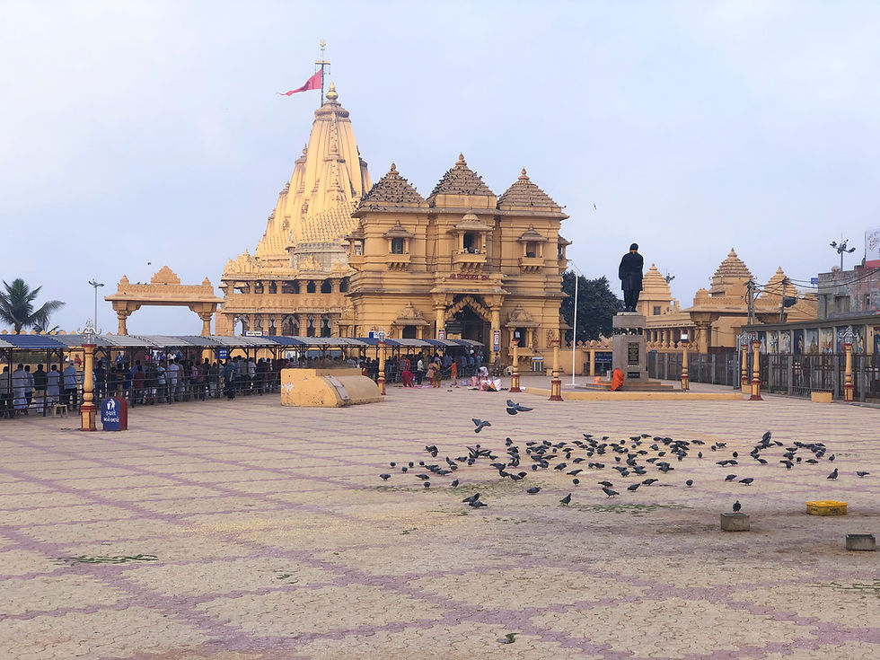 The Shree Somnath Temple complex at dawn, showing the temple tower, a wide courtyard, and few people.