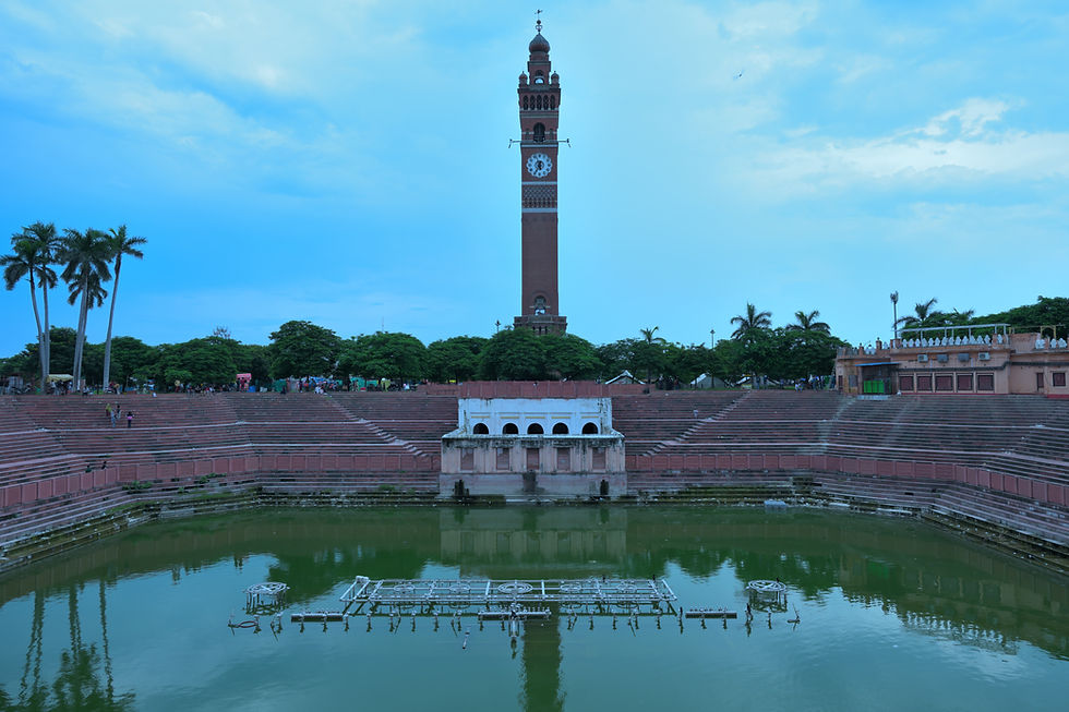 A 24mm architectural shot of the Lucknow Ghanta Ghar (clocktower) standing over a green pond and pavilion. Shot on Nikon Z8 with Nikkor Z 24-120 f/4 S Lens.