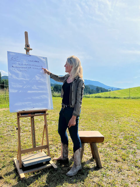 Coach Simone Krebs am FlipChart bei schönstem Wetter draußen. 
