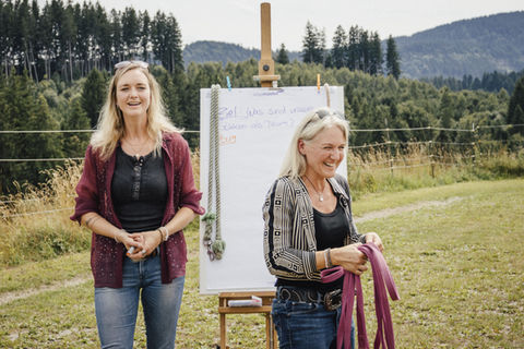 Simone Krebs und Jana Schöpper lachen vor Flip Chart. 
