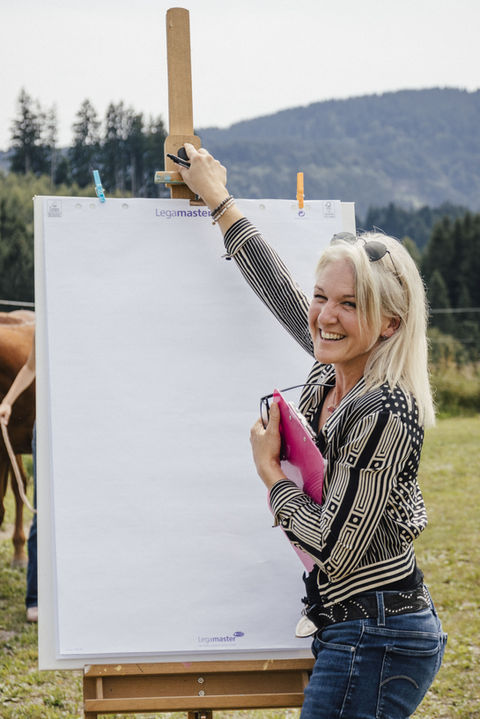 Simone Krebs erklärt lachend an dem Flip Chart. 