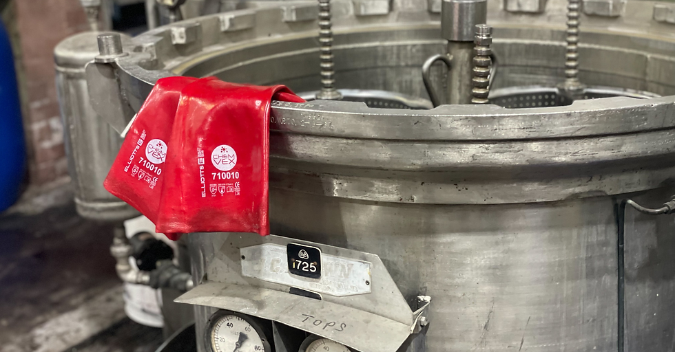 a large metal dyeing vat with red protective gloves resting on edge