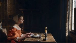 Nella sitting at a table near a window