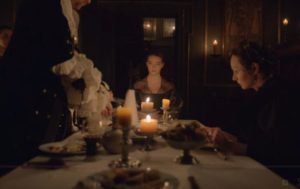 Nella sitting at a dinenr table lit by candles