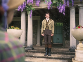 A man standing between two columns with wisteria growing around them