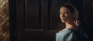 Nella in a blue dress standing near a window