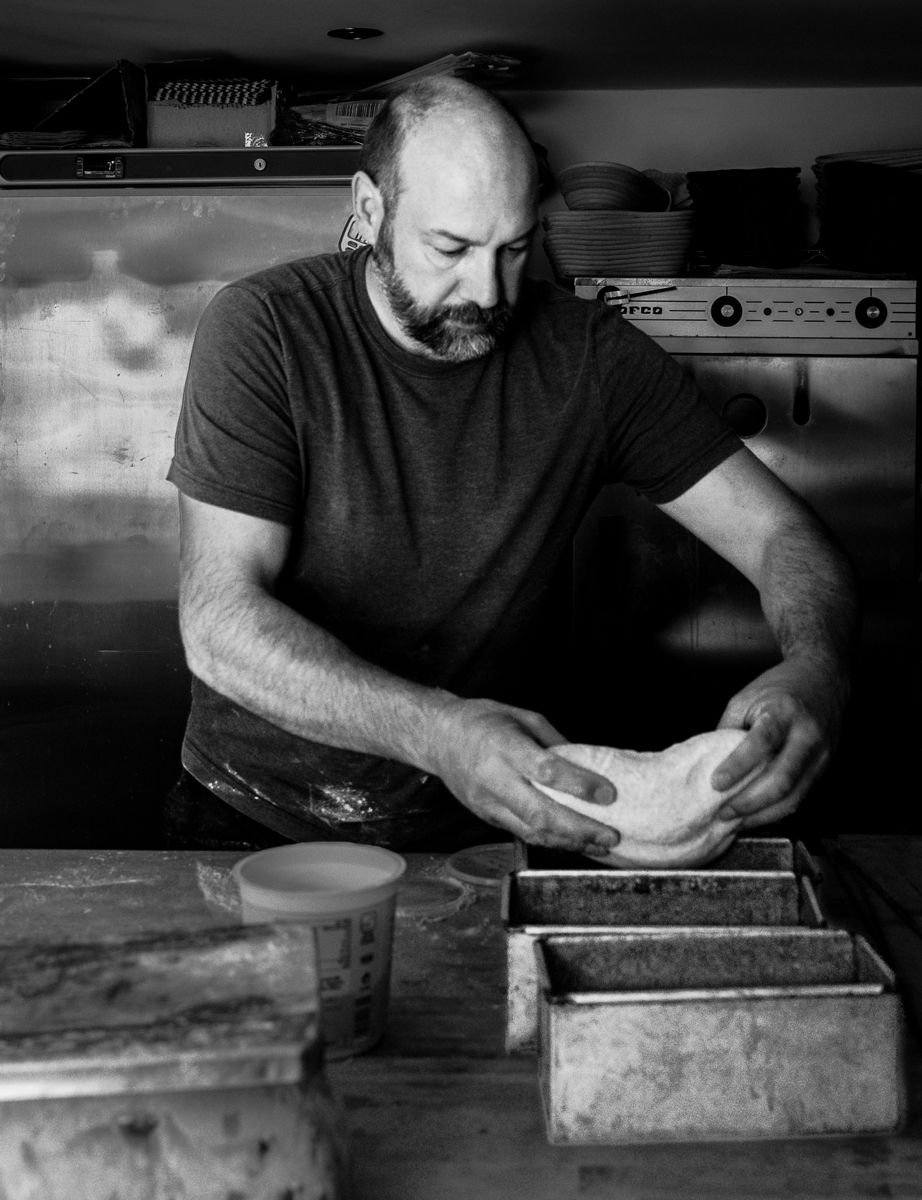 The shaped dough is placed carefully into a loaf tin. Shot in monochrome.