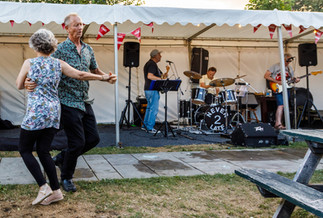Middle aged couple jiving to a three piece band under a gazebo in a pub beer garden