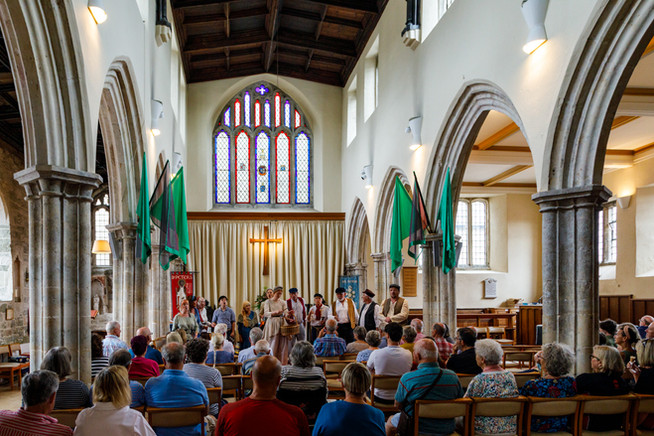 Performers on stage at front of stage singing to a seated audience