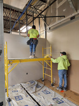 Crew from AJ Drywall on scaffolding installing commercial drywall in Grand Rapids, Michigan.