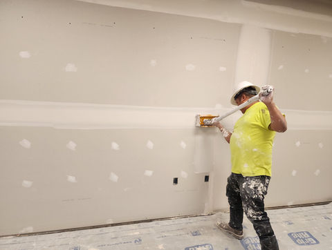 AJ Drywall professional applying joint compound to new commercial sheetrock installation.