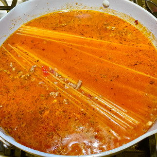 Spaghetti submerged in Bolognese sauce and chicken stock