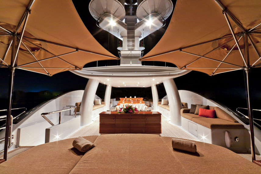 Stylised nightime dining onboard Were Dreams in the open air, top deck of large superyacht.